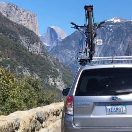 A car with a Yosemite license plate at a turnout on Wawona Road, with Half Dome and El Capitan visible. Photo: Sandra Callan.