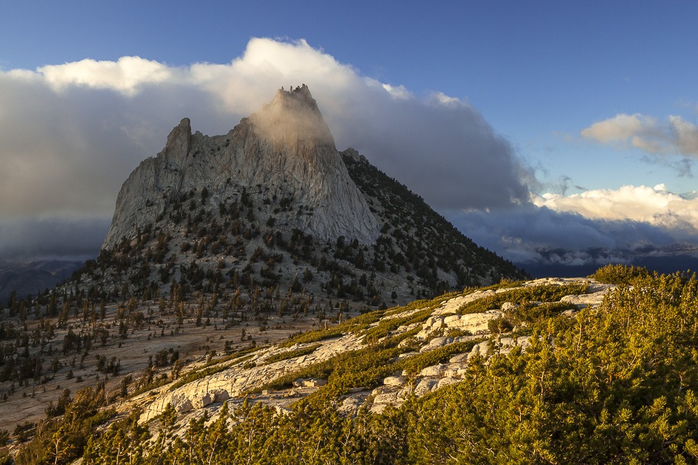 Sculpted by ice and one of the most recognizable landmarks in the Yosemite wilderness, Cathedral Peak juts out from the surrounding landscape as it has for millennia. These granodiorite formations were visible even when ice up to 2,000 feet thick covered the high country during the Tioga glaciation. This is an example of a nunatak, an exposed peak, ridge, or mountain that projects above a surrounding glacier. As the glacier slides past, the sides are slowly carved away, often leaving jagged and sharp crests. The interesting geologic process also creates very photogenic subjects. Cathedral Peak has been featured in many outstanding photographs, usually taken from the lakes below. Searching for a different perspective, I followed an adjacent ridge for a more elevated view. Fortunately, clouds built up in the afternoon, adding another visually interesting element. After shooting the sunset, I happily spent the night out under the stars. 