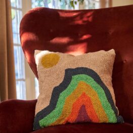 A colorful, decorative throw pillow featuring Yosemite's Half Dome sitting on a maroon arm chair.