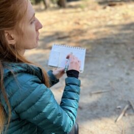 Artist holding up a sketchbook in nature