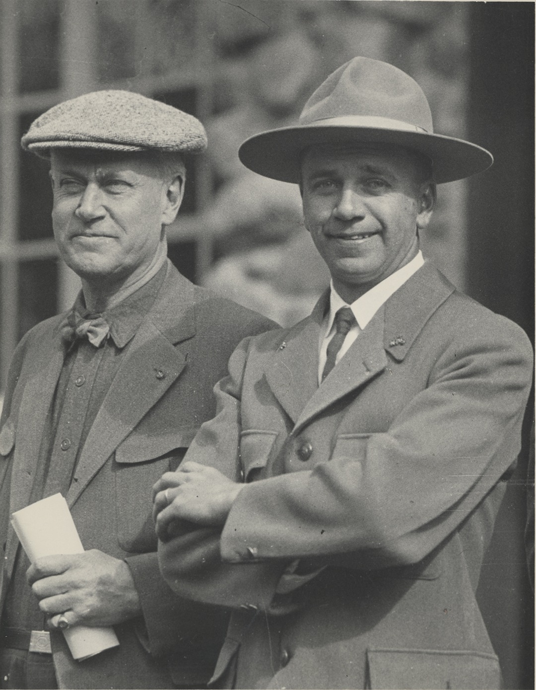 Stephen Mather dressed in street clothes standing along side of park ranger Ansel Hall dressed in uniform at the Yosemite Post Office. Yosemite National Park.