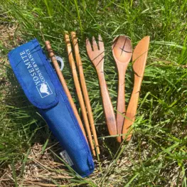 Photo of wooden reusable utensils with blue Yosemite Conservancy pouch laying in the grass