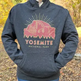 photo of someone wearing a dark grey hoodie with an illustration of Half Dome on it. Text on the hoodie says Yosemite National Park.