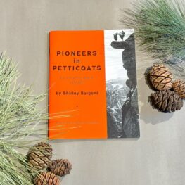 Read Through Yosemite and celebrate Women's History month with Pioneers in Petticoats by Shirley Sargent shown here sitting amongst some conifer foliage. The book is orange on the left and on the right a historic image of two women dancing on a rock overlook. 