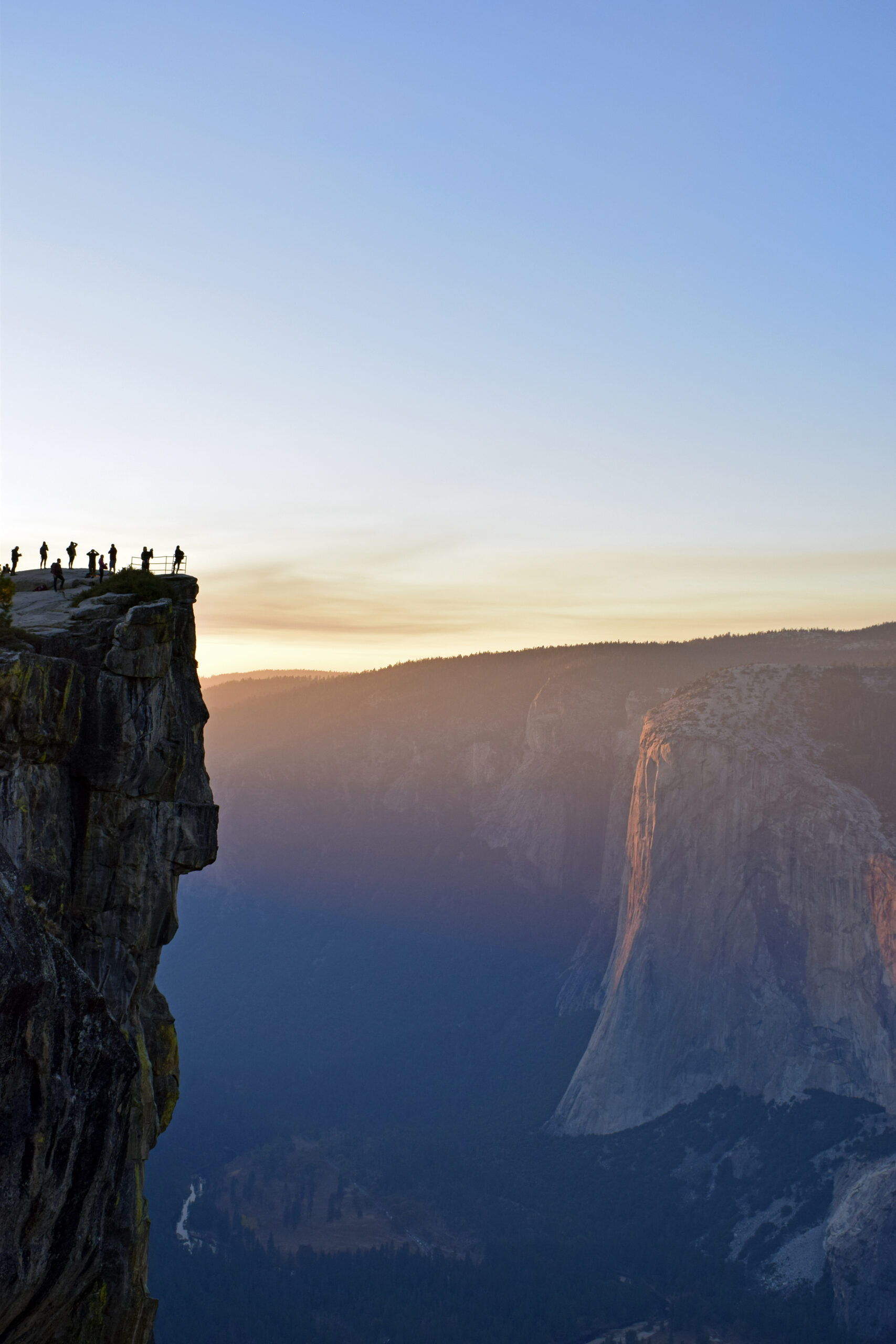Photo at sunset of people standing on cliff