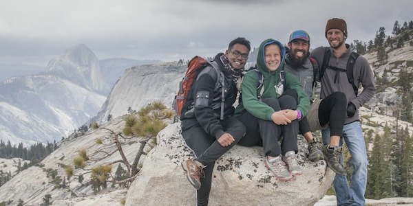 A group of friends on a cloudy spring day at Olmsted Point, with Clouds Rest and Half Dome visible in the background
