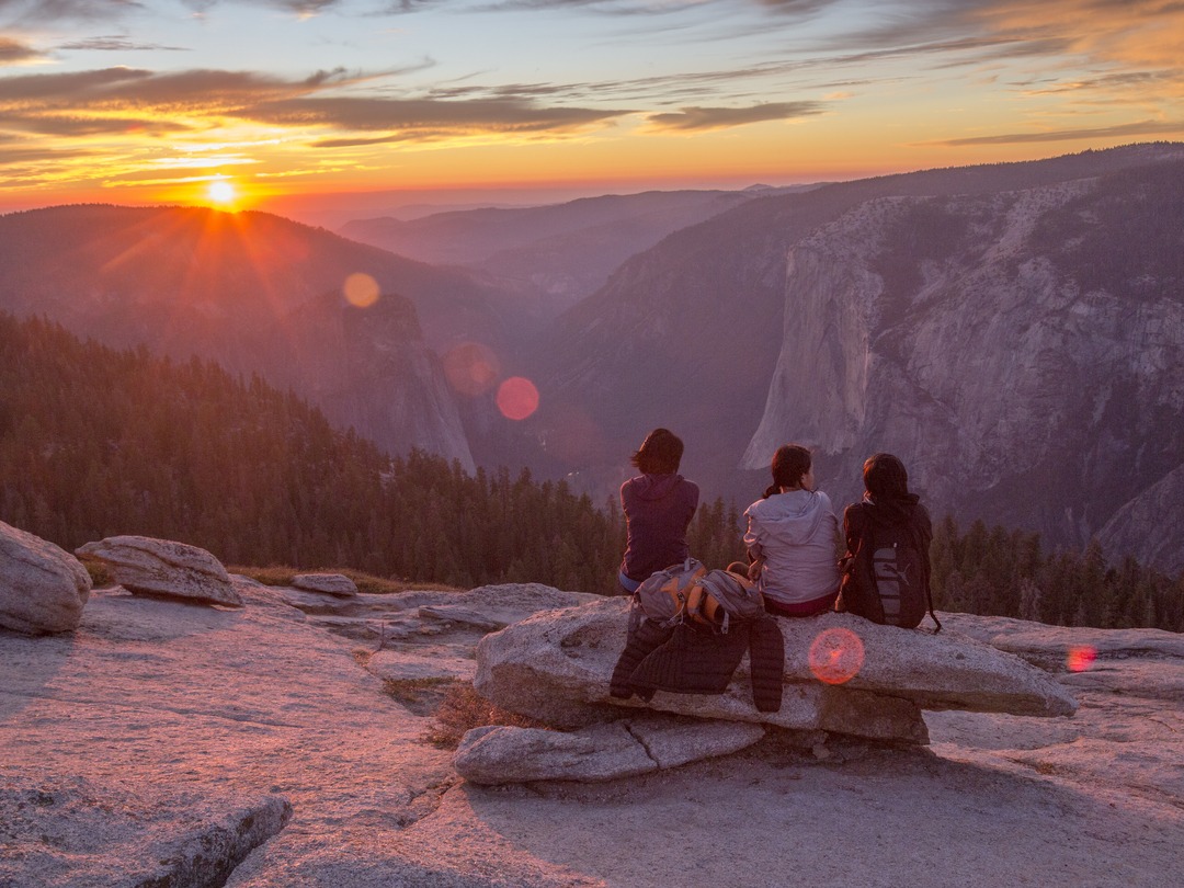 photo of three people watching the sun set over the valley from sentinel dome
