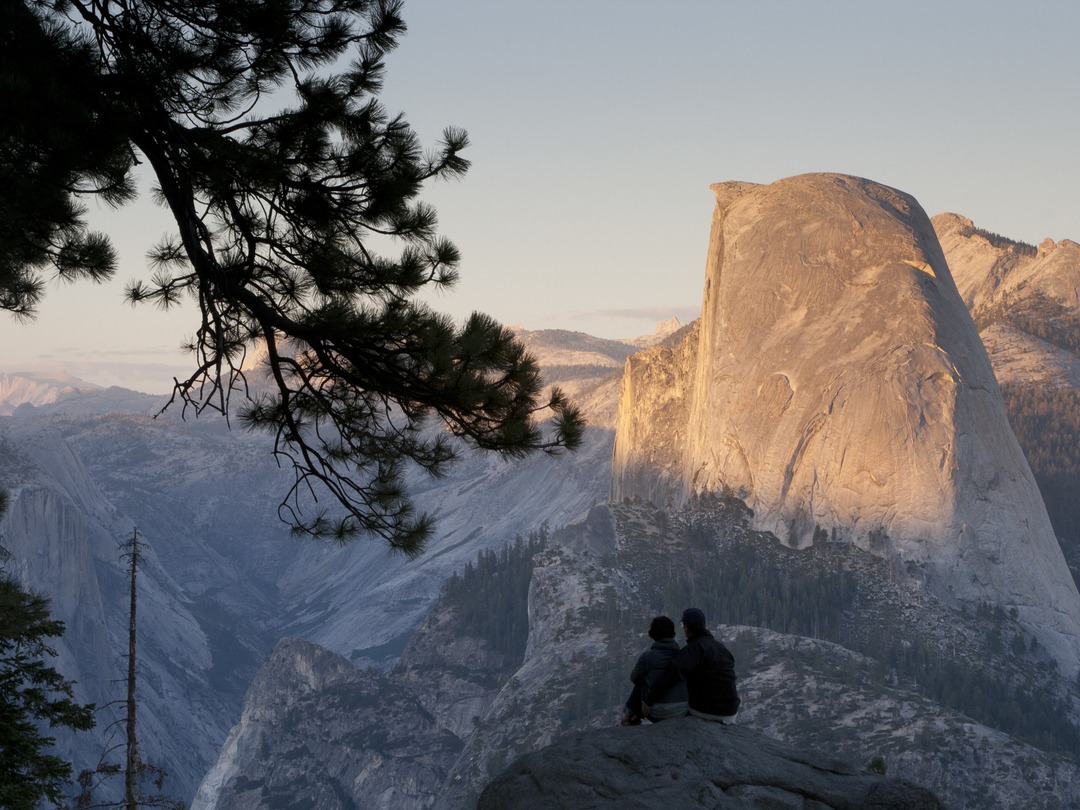 photo of two people watching the sunset on half dome