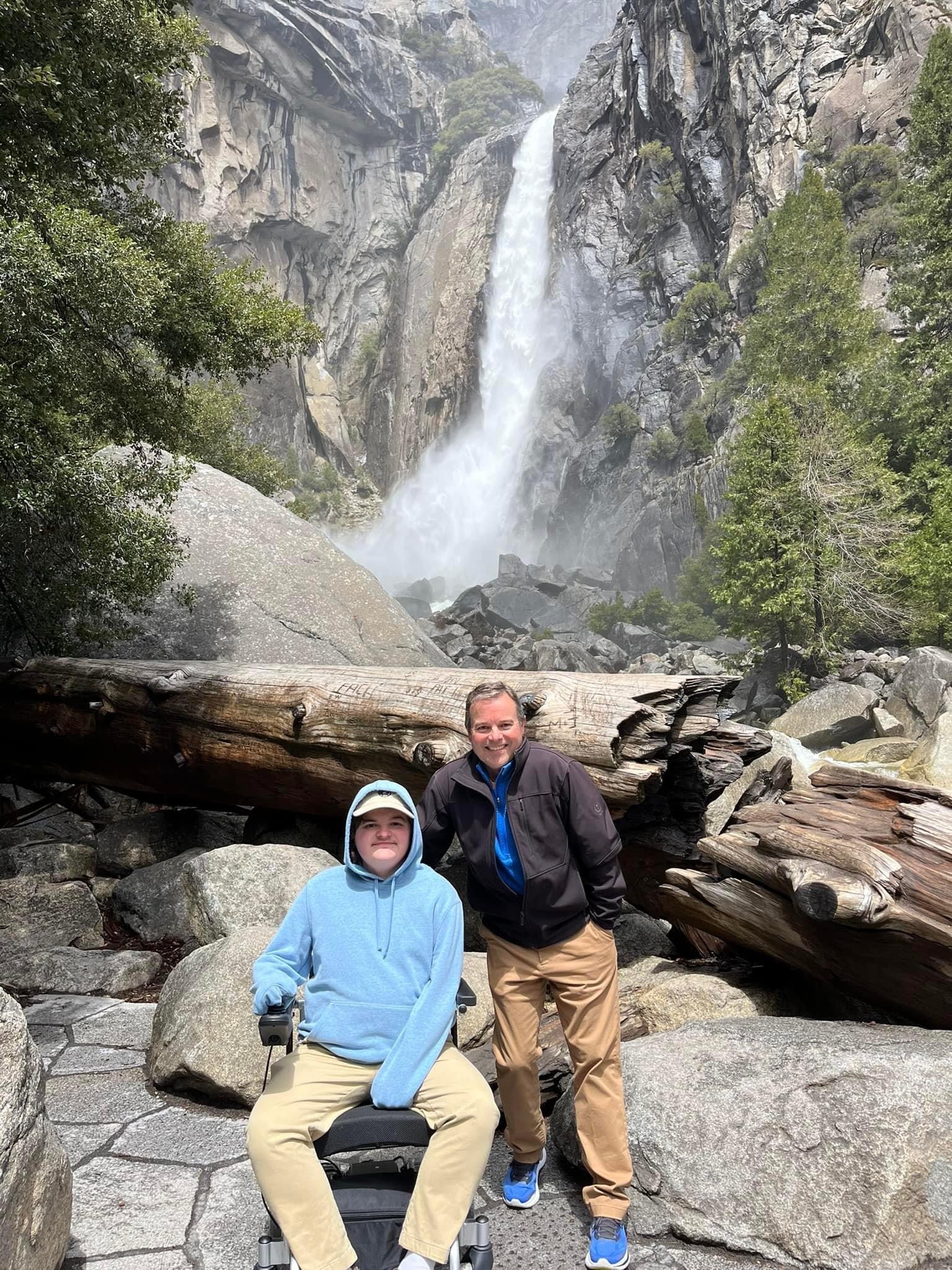 Father and son smiling at Lower Yosemite Fall viewpoint that the son in a wheelchair was able to access. 