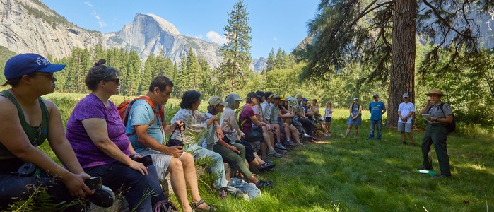 Obata Art Weekend Ranger Talk. Group sitting on a log listening to a park ranger. Half Dome in the background. 