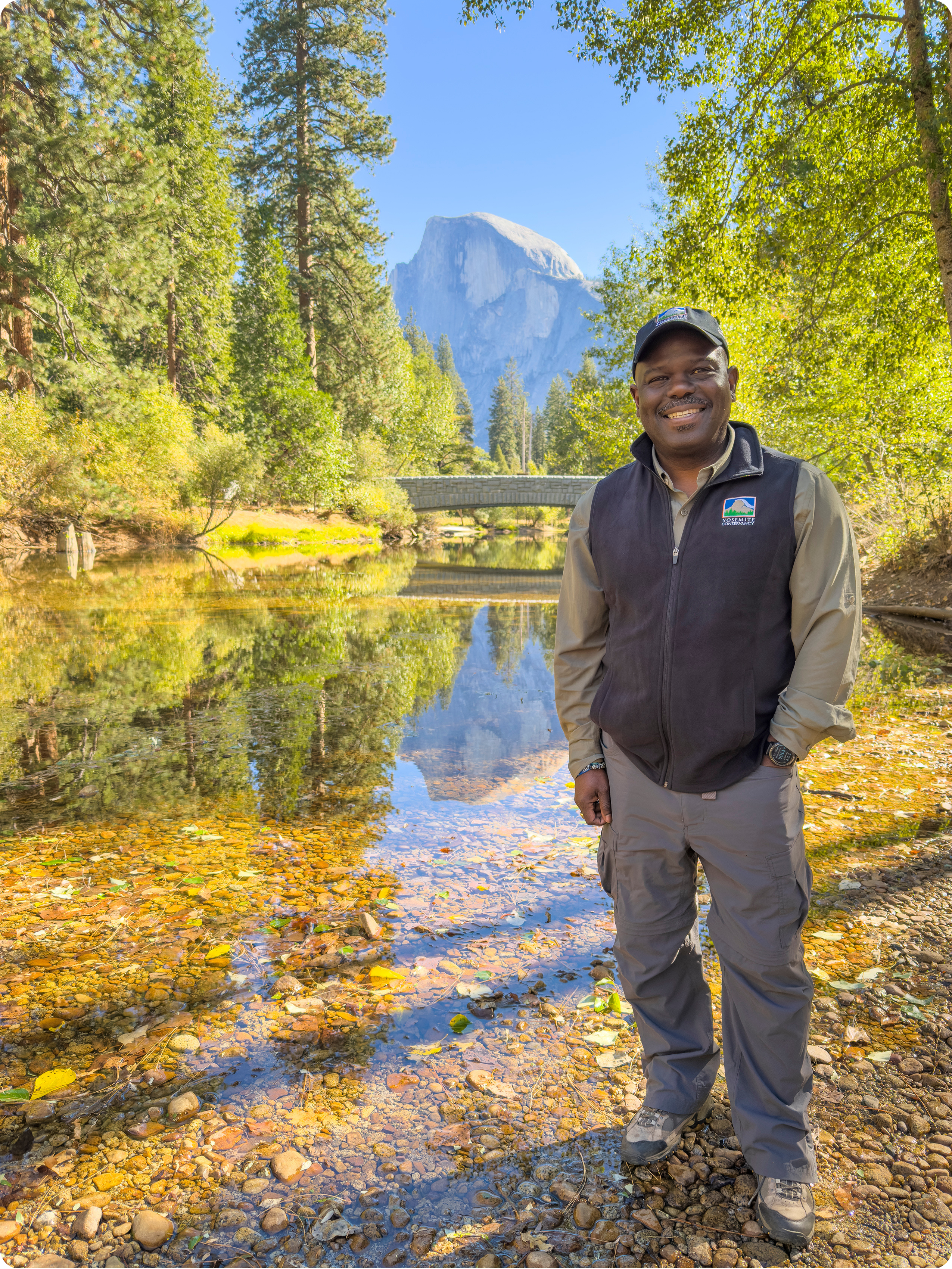 Cassius M. Cash stands in the Merced River with Half Dome in the background.