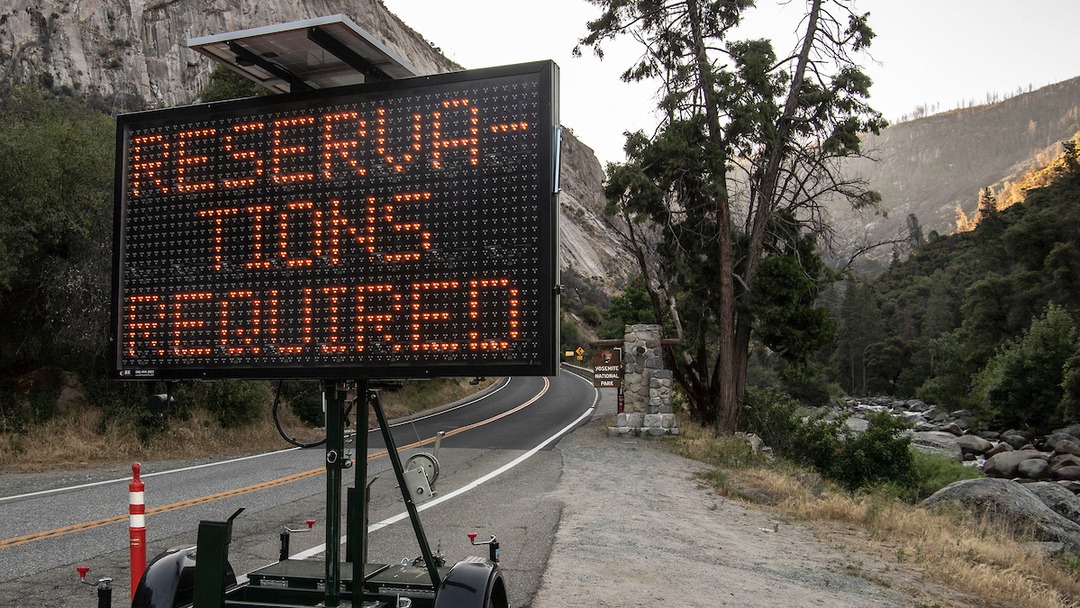 Sign outside Yosemite National Park entrance alerts entering visitors that a peak-hours reservation is required to enter the park