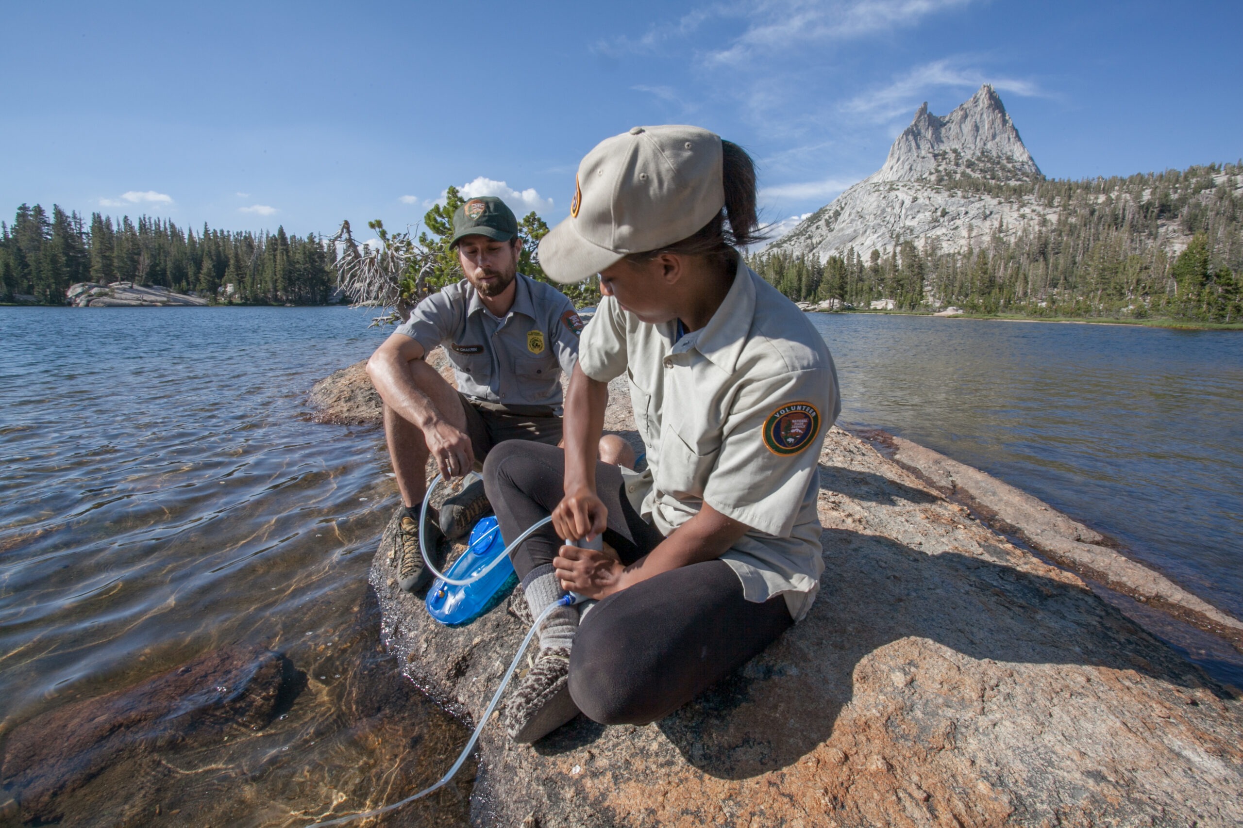 A park ranger shows a volunteer how to filter water during a backpacking expedition.