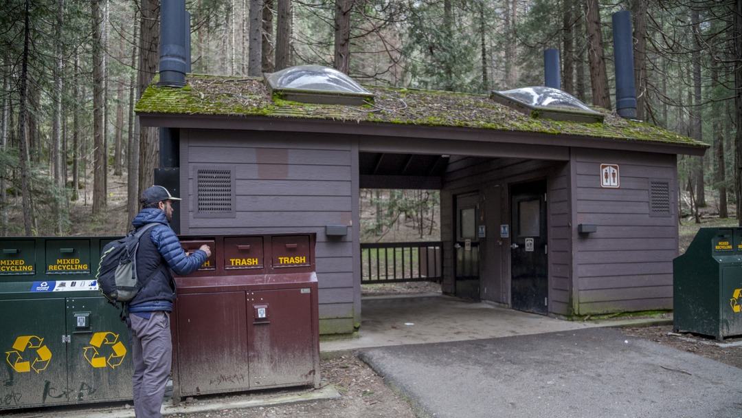 One of many bathrooms in Yosemite. This bathroom is a brown building with two skylights and moss on the roof.