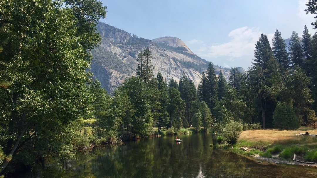 A river twists between trees with granite cliffs in the background.