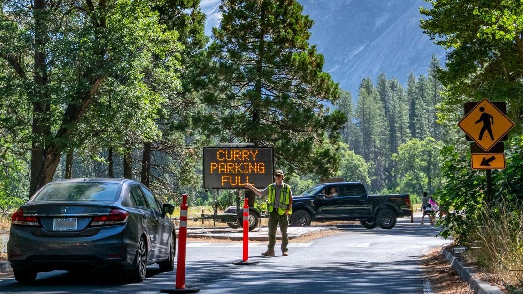 Park staff direct cars to park elsewhere, as the Yosemite parking lot pictured is full.