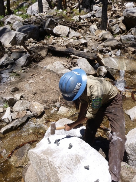 A 2016 CCC crew member splits a boulder while working on trails in Yosemite's backcountry. Photo: Courtesy of NPS.