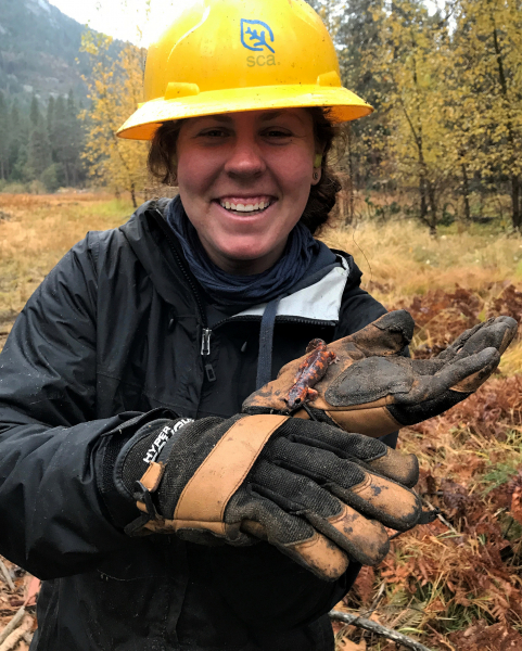 Mackenzie, a 2017 Student Conservation Association intern, takes a break from restoring historic vistas on an autumn day in the Valley to admire an orange and black Sierra Nevada ensatina. Photo: NPS